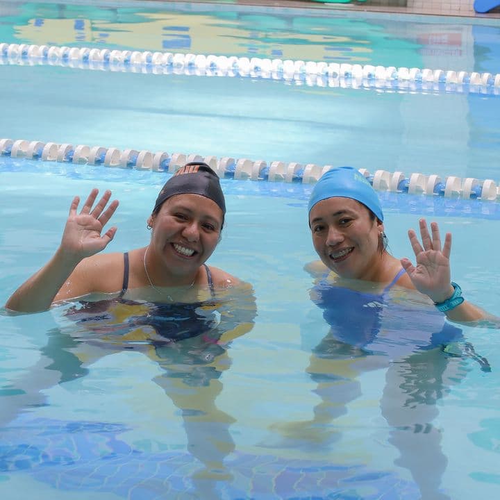 Dos alumnas adultas saludan desde la alberca