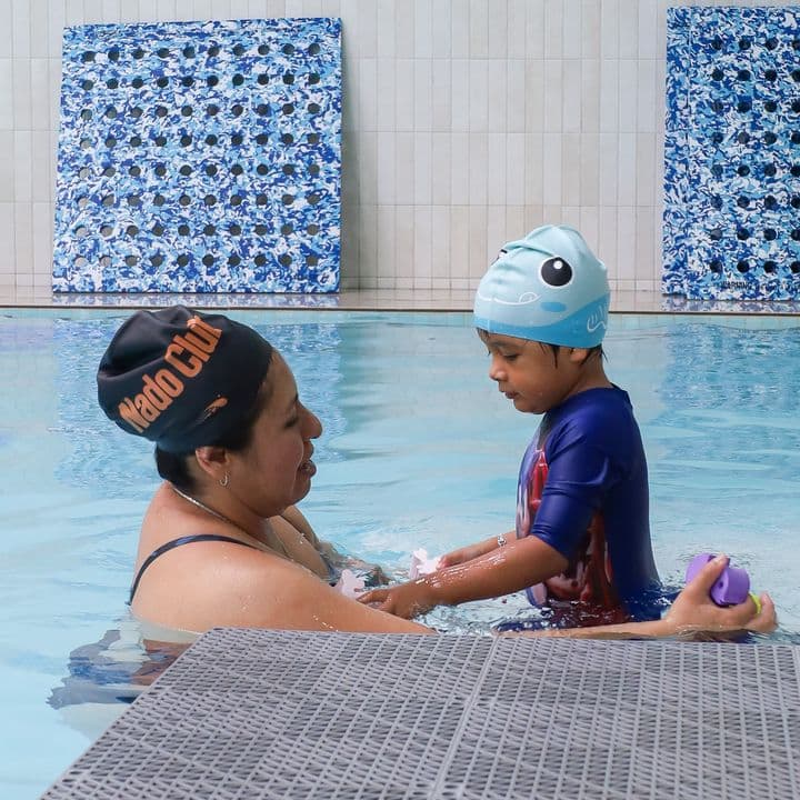 Una mamá y su hijo practican en la alberca