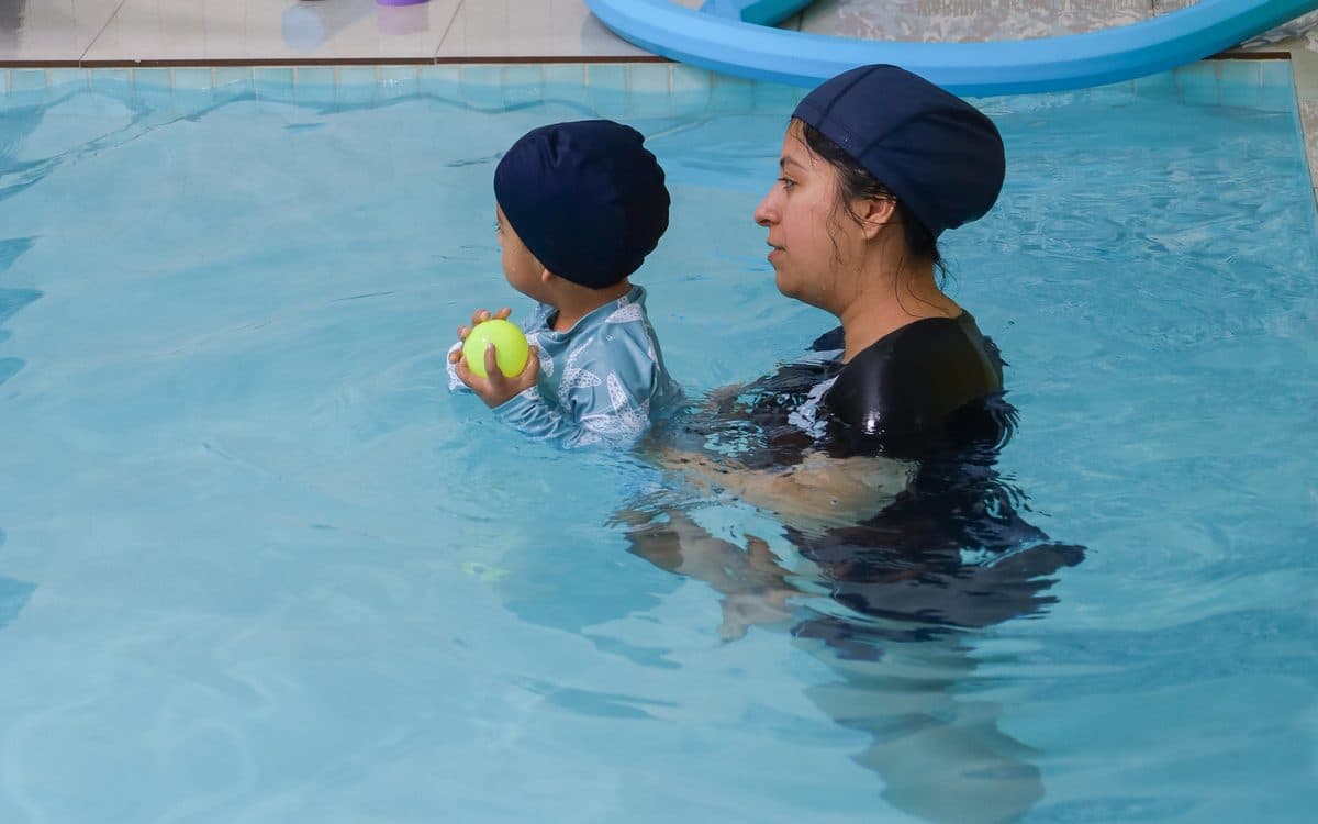 Una instructora en el agua con un bebé que sostiene una pelota